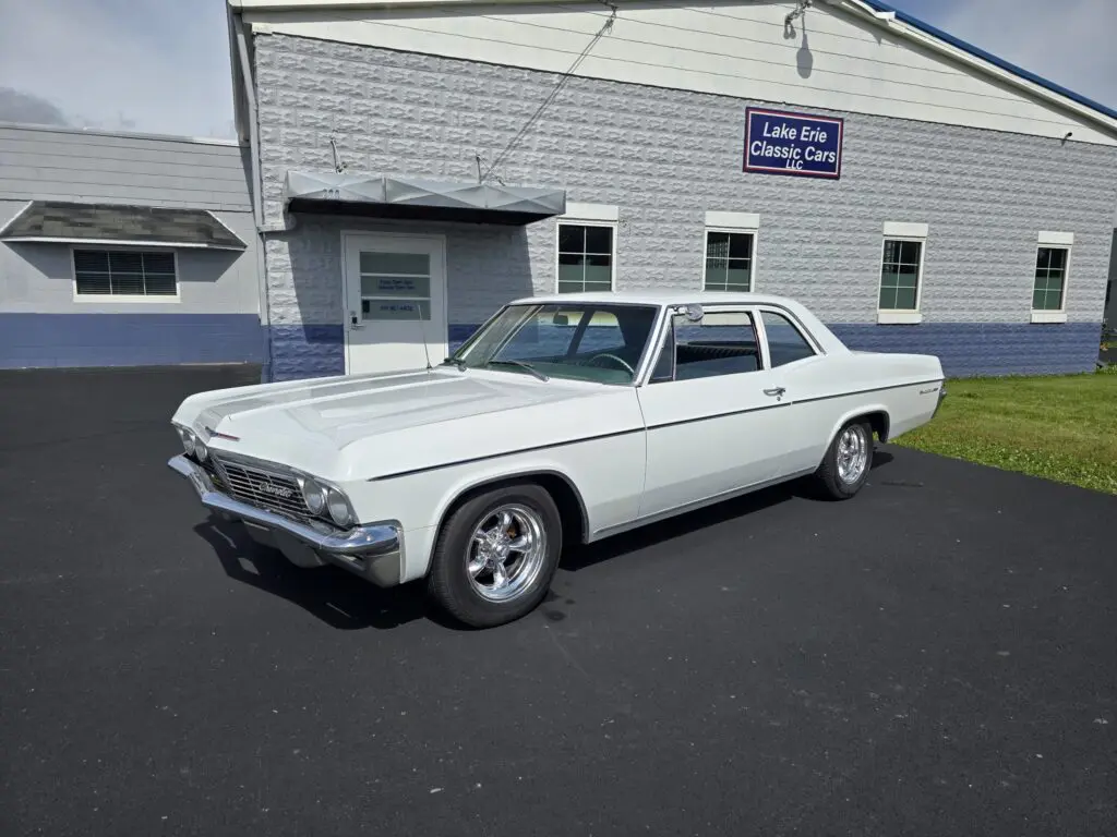 White classic car parked outside a building.
