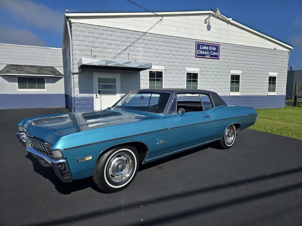 Blue vintage car parked near classic cars.