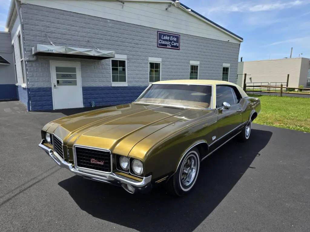 Vintage gold classic car parked outside building.