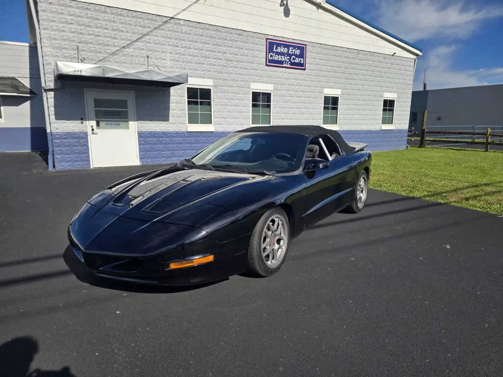 Black sports car parked outside building.